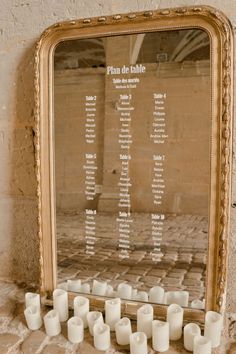 candles are arranged in front of a large mirror on the wall, which is displaying an important table number