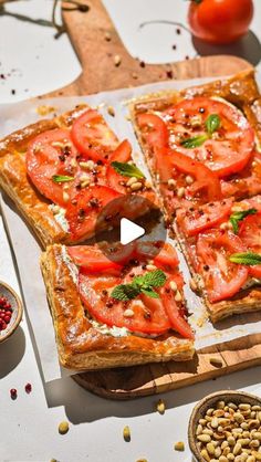 a pizza with tomatoes and other toppings sitting on top of a wooden cutting board