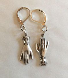 A pair of mixed matched elegant hands two hand earrings created from two Victorian styled findings raw brass gold tone charms For pierced ears with leverback fittings Perhaps a present for an engagement or wedding with the emphasis on hands in both celebrations.  Please note that the hands are identical and therefore not a true 'pair' of hands.  These earrings hang one from the fingers, and the other hangs from the cuff, so it is like giving someone a hug I also have earrings that both hang from the fingers, or a pair that both hang from the cuffs in a choice of metals The charms are single sided stamped metal and are therefore hollow backed and lovely and light to wear Measurement hand 2.5cm long each  See other hand face and eye jewellery Metal Charms Jewelry For Wedding, Silver Brass Jewelry With Lobster Clasp, Metal Drop Earrings With Charms, Metal Charms Drop Earrings, Hand Cast Silver Drop Earrings, Hand Cast Silver Dangle Earrings, Silver Hand Cast Dangle Earrings, Silver Hand Cast Drop Earrings, Hand Cast Metal Jewelry For Weddings