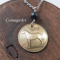 Irish Horse Coin Necklace -Irish Kilkenny Black Marble -20 Pence Domed Coin  -Celtic -Horse Pendant -Equestrian -Irish Jewelry Women  5048 A. The Irish 20 pence coin is made of copper, zinc and nickel which gives it a brilliant gold shine or soft brass color. The image of an Irish Hunter Horse is on one side with the Irish harp on the other. The coin is domed and the mint date is between 1985 and 2000. The Irish Hunter horse is an excellent sport horse, used in hunting, jumping, polo and fox hunting. It is a Thoroughbred. A polished Kilkenny Black marble stone connects the coin to chain. Kilkenny Marble is mined in Southeastern Ireland in Leinster Province.    CHAIN: Brilliant Stainless Steel Cable Chain 18 to 20 inch Adjustable Length with Lobster Claw Closure. CHAIN OPTION: Stunning .925 Celtic Horse, Irish Horse, Hunter Horse, Irish Harp, Horse Pendant, Celtic Necklace, Horse Ornaments, Fossil Jewelry, Irish Jewelry