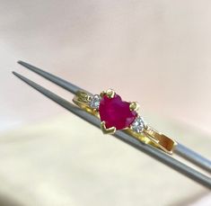 A radiant ruby heart at its center, surrounded with diamonds, securely held in a 3-prong setting, adding a touch of brilliance and elegance. Sized at 7 1/2 |  Be sure to check the Ring Sizes before purchasing! Details: Stone: Diamond ruby heart. 3 prong setting  Metal: 14K  Yellow gold, stamped for authenticity Ring size: 7 1/2 Feel free to message us anytime if you have any questions in mind. Anniversary Yellow Gold Ruby Ring With Heart Shape, Valentine's Day Yellow Gold Solitaire Diamond Ring, Heart Cut Ruby Jewelry With Prong Setting, Anniversary Yellow Gold Heart Ruby Ring, Ruby Heart Ring With Center Stone For Anniversary, Anniversary Ruby Ring With Heart Cut And Prong Setting, Heart Cut Ruby Ring With Prong Setting For Anniversary, Heart Cut Ruby Ring In Yellow Gold For Wedding, Valentine's Day Oval Diamond Ring With Prong Setting