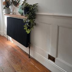 a radiator in the corner of a room with two potted plants on it