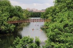 people are kayaking on the river under a bridge