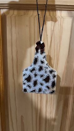 an oven mitt hanging from a wooden door with a brown bow on it's neck