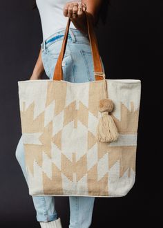 You'll be ready for your next getaway with our tote collection! This cream and tan Aztec inspired large tote is just what you need for an upcoming vacation, or for running errands.  Cream and tan Aztec inspired tote Tan pom tassel detail Leather suede straps Measures 16" x 6" x 16" Designed in the U.S.A. Produced in India. 100% Cotton Lining: 100% Polyester White Weekender Shoulder Bag With Leather Handles, White Leather Handled Tote Travel Bag, Beige Tote Travel Bag With Leather Handles, Beige Leather-handled Tote Travel Bag, Beige Tote Weekender Bag With Handles, Large Capacity Cream Tote Weekender Bag, Cream Canvas Vacation Bag, Cream Satchel Beach Bag For Everyday Use, Bohemian Cream Beach Bag For Travel