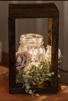 a mason jar filled with flowers sitting on top of a wooden table next to a candle