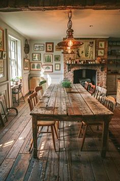 a wooden table with chairs around it in front of a fire place and pictures on the wall