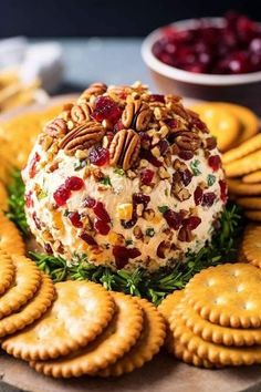 a cheese ball with crackers and cranberries on the side sitting on a platter