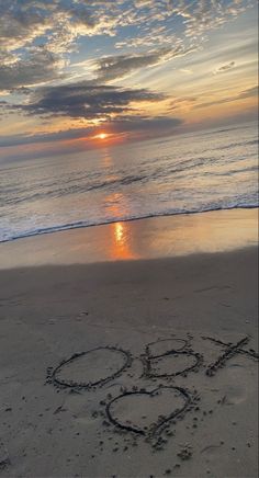 the word love is written in the sand at the beach as the sun goes down