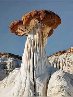 a very large mushroom like structure in the middle of some desert land with ice hanging off it's sides