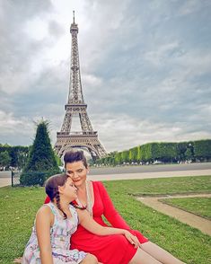 two people sitting on the grass in front of the eiffel tower, paris