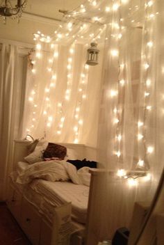 a bedroom with lights strung from the ceiling and curtains over the bed in front of it