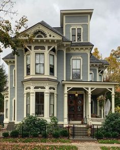 a large blue house with white trim on the front door and two story porches