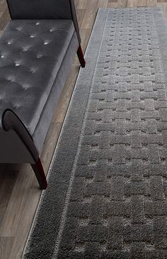 a living room area with a couch, chair and rugs on the hardwood floor