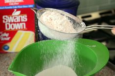 a person pouring flour into a green bowl