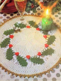 a doily with holly leaves on it and a lit candle in the center surrounded by candlesticks