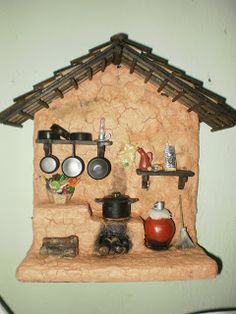 a clay house with pots and pans on the shelf next to it's cooking utensils