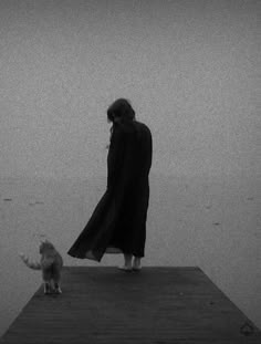 a woman standing on top of a pier next to a cat