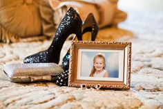 a pair of high heeled shoes sitting on top of a bed next to a framed photo