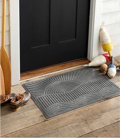 a pair of shoes sitting next to a door mat on the front porch with two paddles