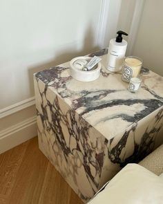 a marbled table with soap and lotion on it next to a white chair