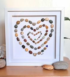 a heart made out of rocks sitting on top of a wooden table next to two sea shells