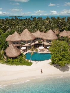 an aerial view of a beach resort with thatched roofs and palm trees in the background