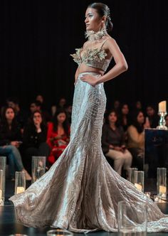 a model walks down the runway in a silver gown