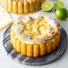 a cake sitting on top of a plate next to limes