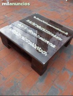 a coffee table made out of glass and wood with writing on the top, sitting on a brick floor