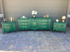 three green dressers sitting next to each other in front of a garage door with flowers on top