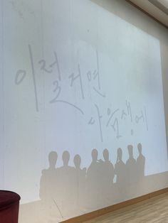 a group of people standing in front of a whiteboard with writing on it and an orange trash can