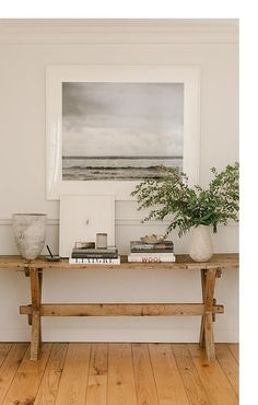 a wooden table topped with books next to a potted plant