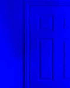 a blue door in a room with a black cat sitting on the floor next to it