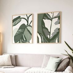 two paintings hang on the wall above a white couch in a living room with pillows