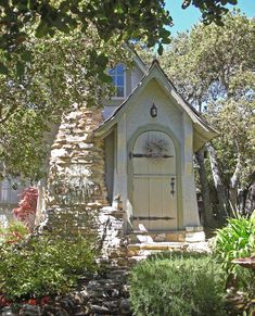 a small house made out of rocks and stone with a door in the center surrounded by trees