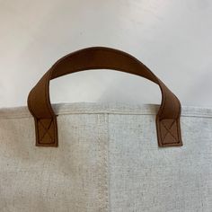 a bag with two handles on it sitting against a white wall and the bottom part of the bag is brown