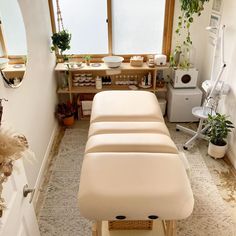 a room filled with lots of plants next to a white table and chair in front of a window