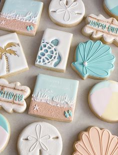 some decorated cookies are laying on a table with sand dollar signs and seashells