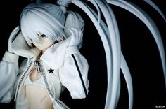 a doll with white hair is posed in front of many wires and cords on her head