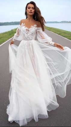 a woman is walking down the road wearing a white dress with sheer sleeves and an open back