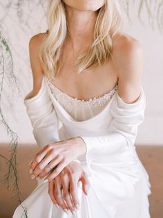 a woman in a white dress is posing for the camera with her hands on her knees