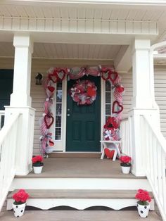 a front porch decorated for valentine's day with wreaths and flowers