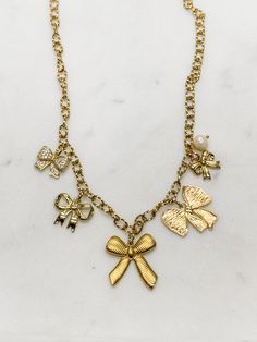 If you love a classic bow, this fun charm necklace is your vibe! Handcrafted in our studio from 18k gold-plated steel elements. --18" in length and will clasp shorter as desired --Hypoallergenic --Tarnish resistant --Plated in genuine 18k gold --Trendy design, but with the timeless appeal of bow ribbons These will be limited, so get yours while it's available! Elegant Butterfly Charm For Gift, Elegant Gift Charms With Adjustable Chain, Elegant Gold Charm Necklace With Butterfly, Chic Gold Necklace With Bow, Gold Charm Necklaces With Lobster Clasp For Party, Gold Charm Necklace With Lobster Clasp For Party, Gold Charm Necklace For Party, Chic Gold Necklaces With Charms, Elegant Gold Charm Necklace With Dangling Charms