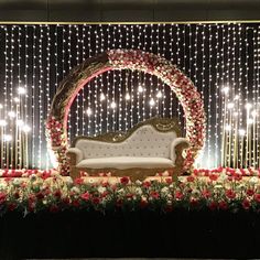 a decorated stage set up for a wedding with white couches and red flowers on it