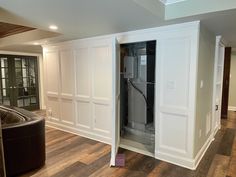 an empty room with white cabinets and wood flooring in the center is a black leather chair