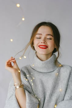 a woman with her eyes closed is smiling and holding sparklers in front of her face