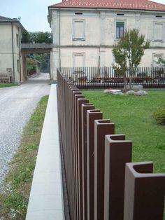 a long metal fence is in front of an old building with a red tiled roof