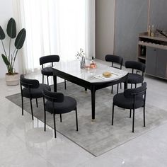 a dining room table with black chairs and a white marble top in front of a large window