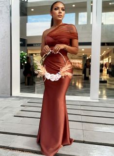 a woman in a red dress is holding a flower and wearing a headpiece with feathers on it